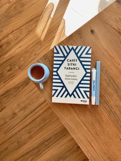 A book, cup of coffee, and pen arranged on a wooden table for a cozy reading atmosphere.