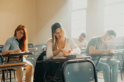 Focused students taking an exam in a sunlit Buenos Aires classroom with a relaxed academic atmosphere.