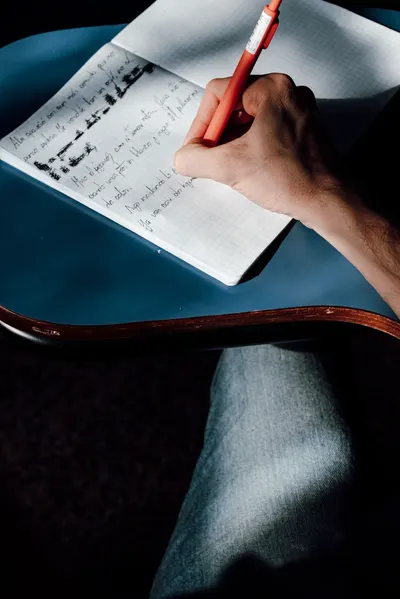 A person writing notes in a notebook, emphasizing education and learning.