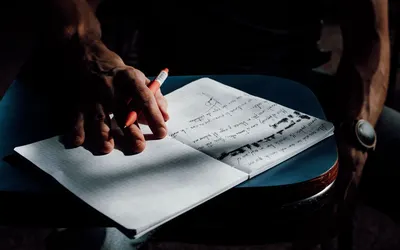 Close-up of a student writing in a notebook with ambient lighting, capturing a moment of academic focus.