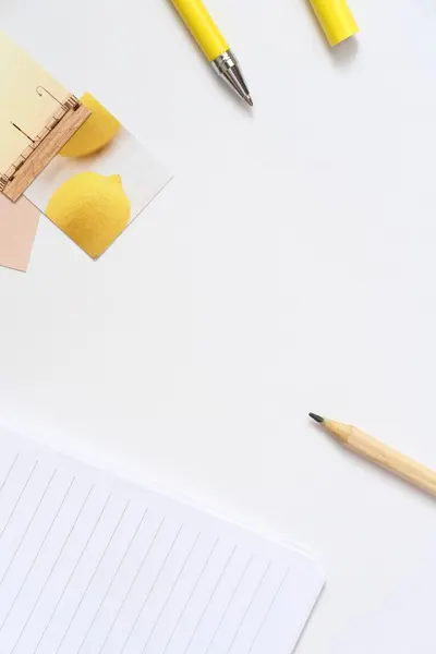 Flat lay of yellow stationery items on a white desk for a minimalist and organized workspace.