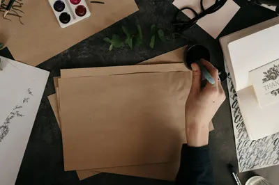 Hand crafting calligraphy on paper with ink and eucalyptus on a desk.