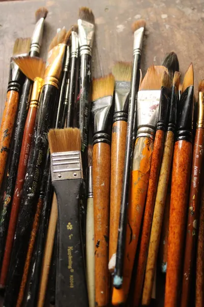 Various paintbrushes grouped on a wooden table, ideal for artists and creativity themes.