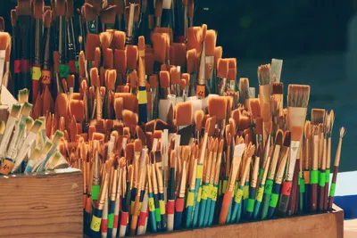Collection of paintbrushes in a wooden holder, perfect for art projects.