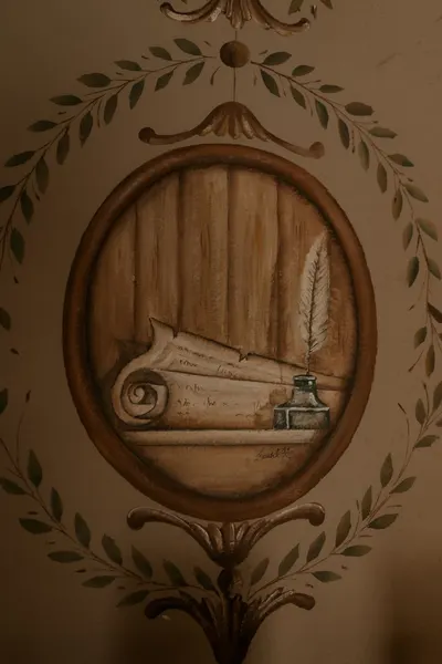 Elegant vintage mural featuring a quill and ink set against a roll of parchment, framed within an ornate oval.