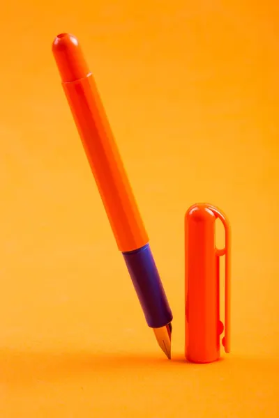 Vibrant orange fountain pen and cap on matching background, showcasing minimalist design.