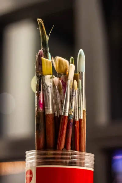 Detailed view of used paint brushes in a red holder, ideal for art-related visuals.