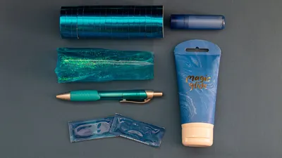 A top view of blue-themed stationery and personal care items, including a pen and magic glide tube.