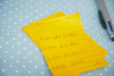 Close-up of yellow sticky notes with handwritten Korean text on polka dot fabric.