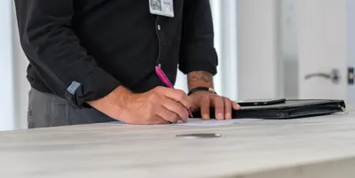 A businessman signing documents at a modern office desk with a focus on hands and workspace.
