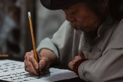 Elderly man practicing traditional calligraphy in Vietnam.