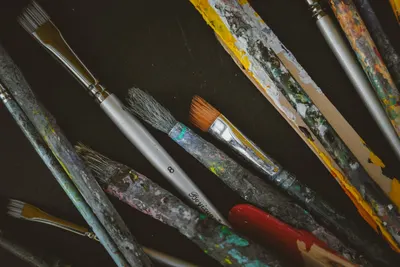 A variety of used paintbrushes with dried paint, showcasing creativity and mixed media art.