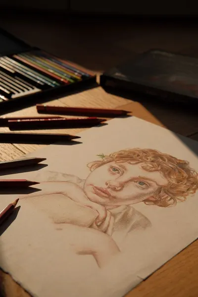 A detailed portrait drawing with colored pencils lit by warm natural sunlight.