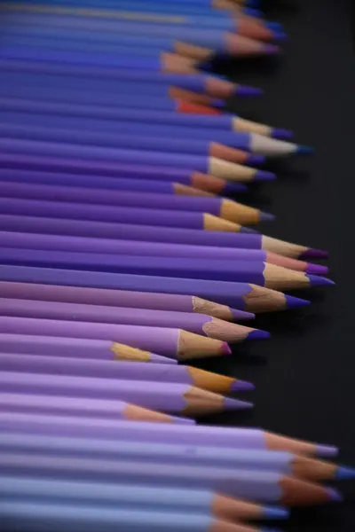 Aesthetic arrangement of purple pencils creating a gradient effect on a dark background.