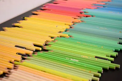 Vivid collection of colored pencils arranged in a rainbow spectrum on a flat surface.