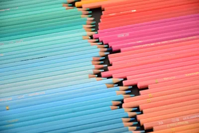 Vibrant gradient arrangement of colored pencils in blue and pink hues.