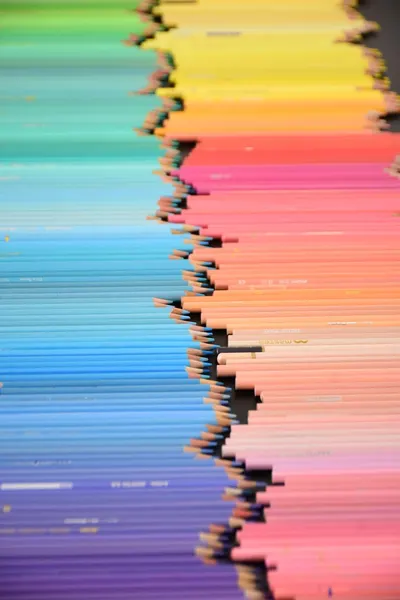 Close-up of neatly arranged vibrant colored pencils creating a rainbow spectrum.