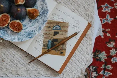 A vintage setup of figs on lace with a notebook and photo, evoking nostalgia.