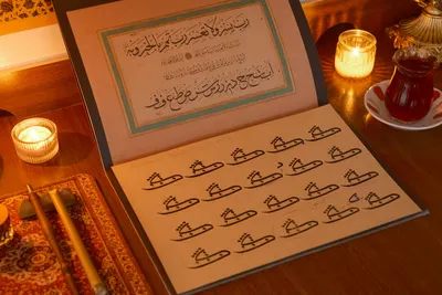 Beautiful Arabic calligraphy display on a wooden desk with tea and candles, creating a warm ambience.