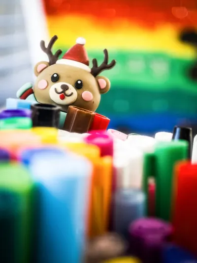 A charming reindeer figurine amidst vibrant art supplies, evoking a festive and creative mood.