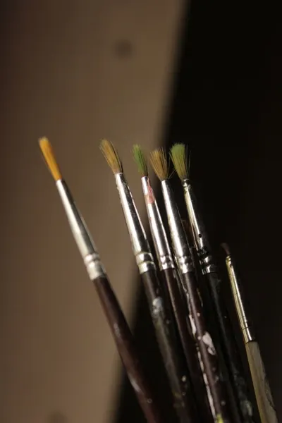 Artistic display of various painters' brushes in a studio setting.