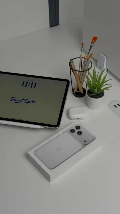 Stylish workspace with a tablet, smartphone box, and plant on a white desk.
