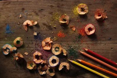 A vibrant display of pencil shavings and colored pencils on a wooden table.