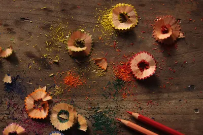 Vibrant pencil shavings and colorful debris on a rustic wooden surface.