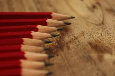Close-up of aligned red pencils on a wooden texture, perfect for artistic and educational themes.