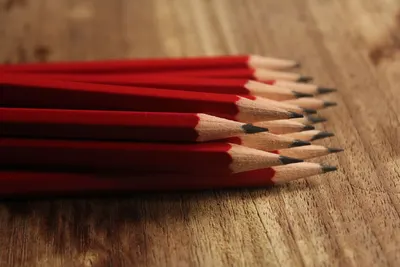 A collection of red pencils neatly arranged on a wooden surface, showcasing sharp tips.