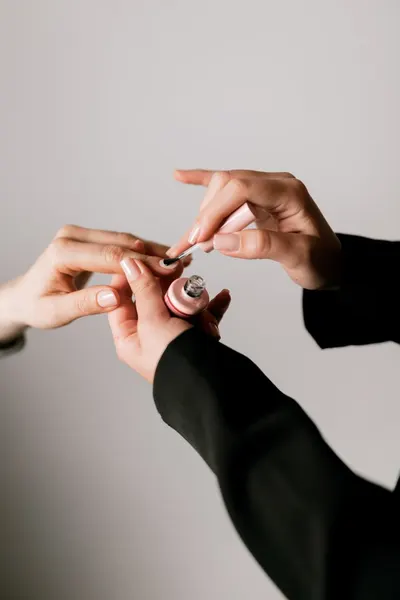 Close-up of elegant hand applying nail polish, capturing the essence of beauty and self-care in soft lighting.