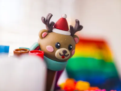 Cute reindeer toy with Santa hat and rainbow colors in festive setting.