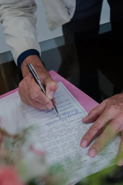 Detailed image of a person signing a formal document with a pen, highlighting business or legal context.