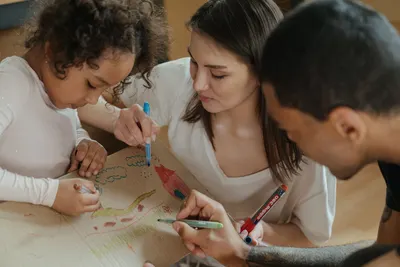 A family drawing together on cardboard, expressing creativity and spending quality time.