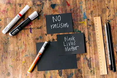 Creative activism cards with 'No Racism' and 'Black Lives Matter' messages on a rustic workbench.