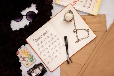 Flat lay of a quarantine countdown notepad with fashion accessories and a vintage watch.