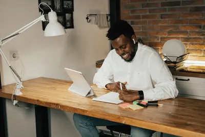 Confident adult enjoying online learning in a cozy home setting with digital tools.