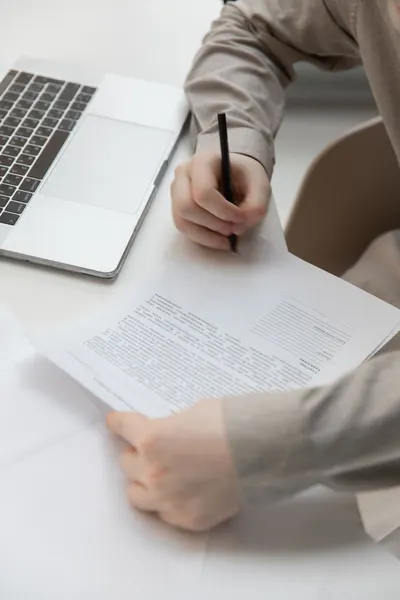 From above of crop unrecognizable male employee singing document near netbook on table in office