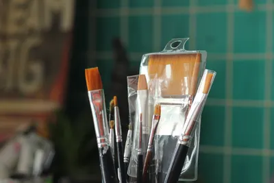 A collection of new paint brushes in a plastic container, ideal for art projects.