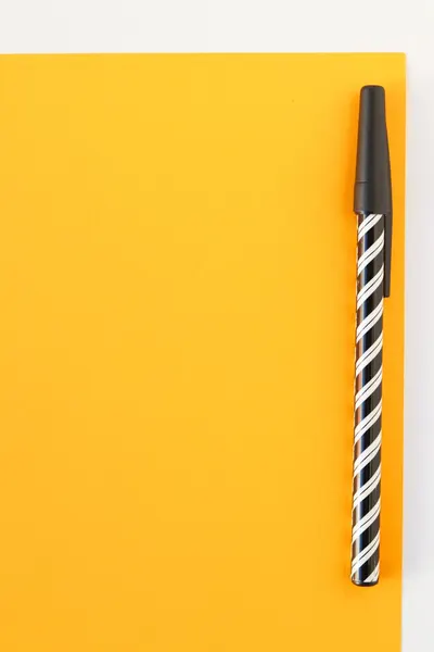A black pen with a white swirl design resting on a vibrant yellow paper, captured in a minimalist style.