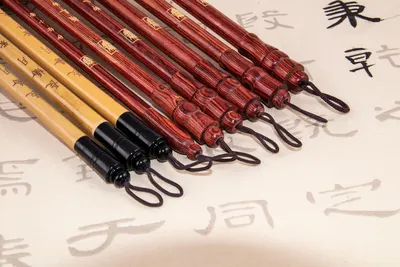 From above of assorted Japanese calligraphy brush pens with loops on edges on paper with hieroglyphs