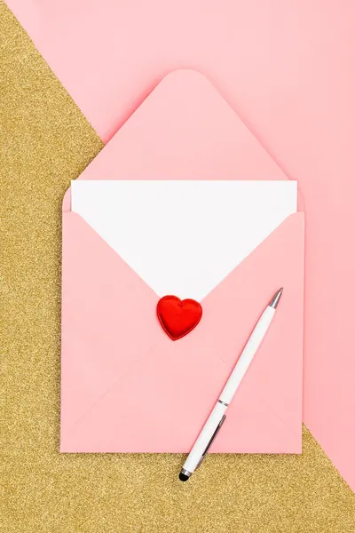 A pink envelope with a heart-shaped seal and pen on a glittering backdrop.