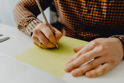 A person writing on yellow paper with a pen, capturing a moment of creativity and expression.