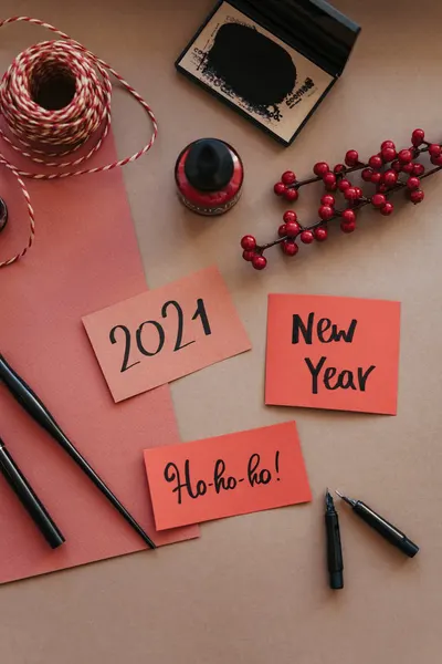Flat lay of calligraphy tools with festive cards and decorations for New Year 2021.