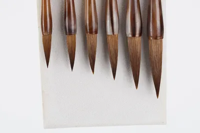 Elegant display of Japanese calligraphy brushes with wooden handles on a white background.