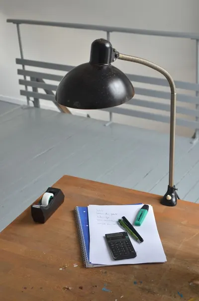 From above of wooden table with lamp papers calculator and sellotape in dispenser on workplace