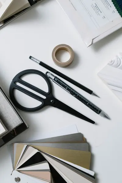 Flat lay of art supplies with scissors, swatches, and stationary for creative work.
