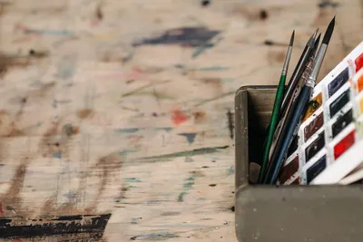 Close-up of watercolor paints and brushes in a workshop setting.