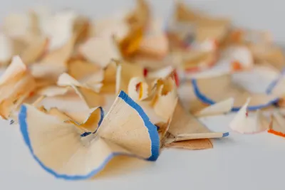 Close-up view of vibrant pencil shavings on a white surface, showcasing artistic detail.