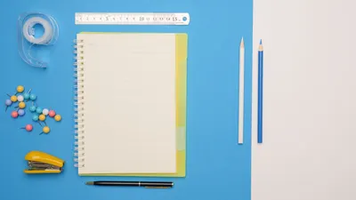 A stylish arrangement of colorful office supplies including a notepad and pencils on a blue background.